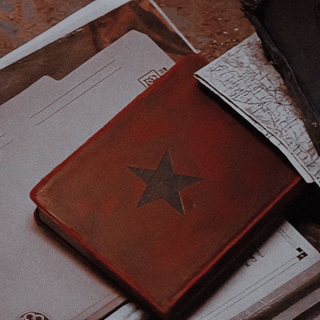 an old red book with a star on it sitting on top of some other books