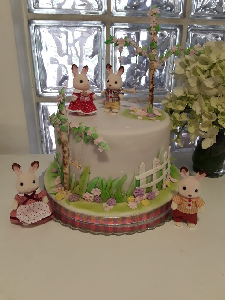 there is a cake decorated with animals and flowers on the table next to a window