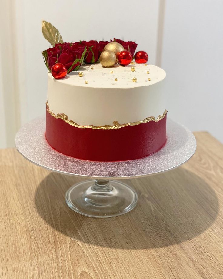 a red and white cake with gold decorations on top is sitting on a glass plate