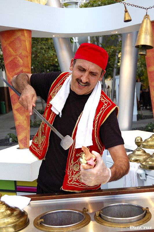 a man in red and white cooking food on top of a stove with tongs