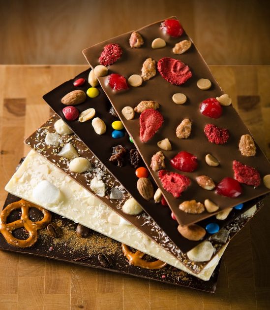 a stack of chocolate bars topped with nuts and pretzels