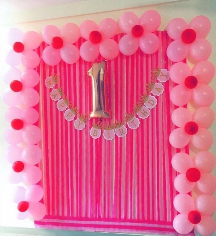 a pink backdrop with balloons and a number one on it