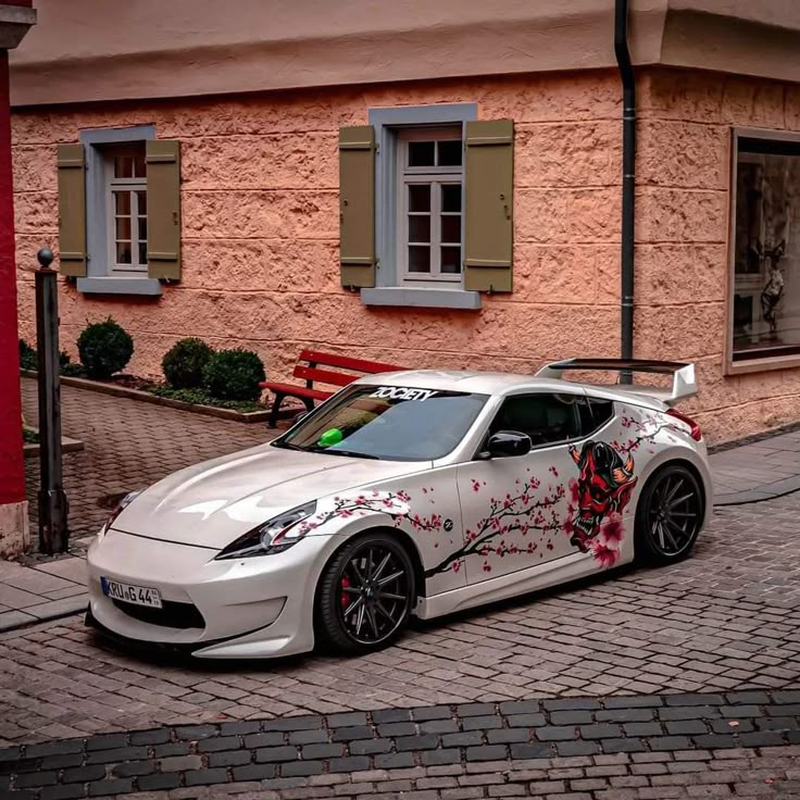 a white sports car parked in front of a building with graffiti on it's side