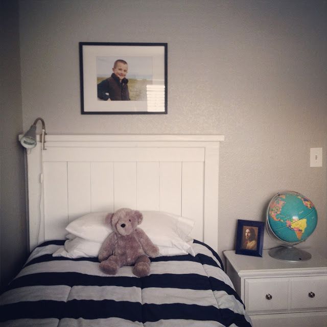 a teddy bear sitting on top of a bed next to a night stand and dresser