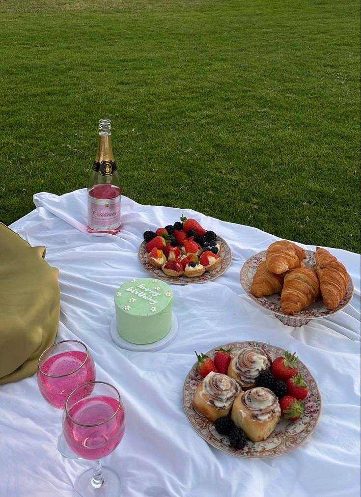 a table topped with cakes and pastries on top of a white cloth covered field