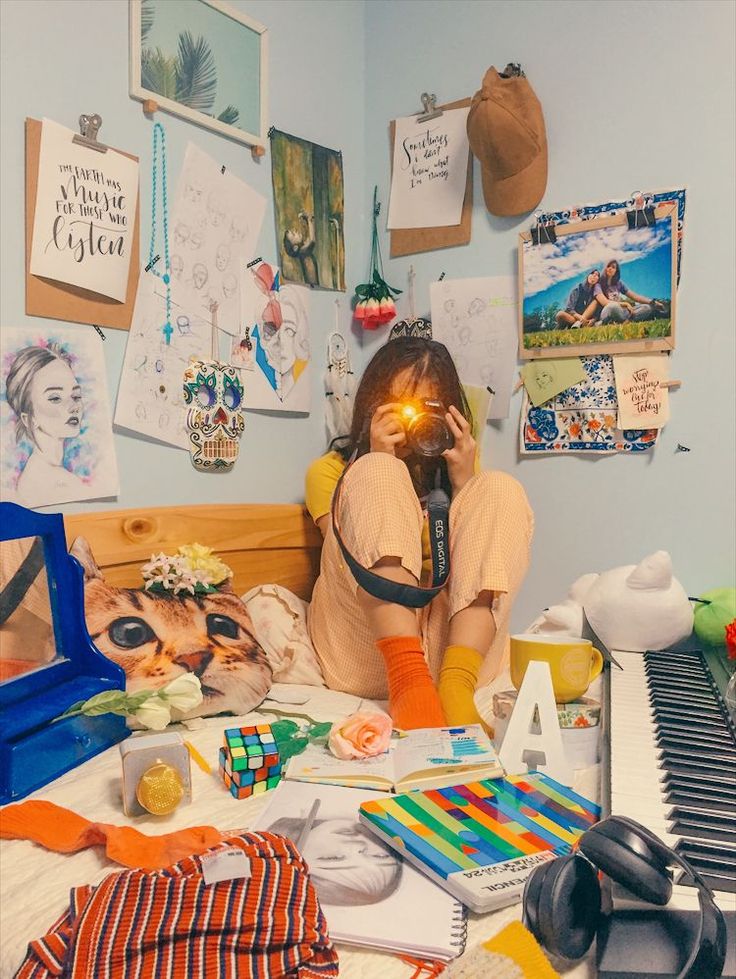 a woman sitting on top of a bed next to a piano and lots of clutter