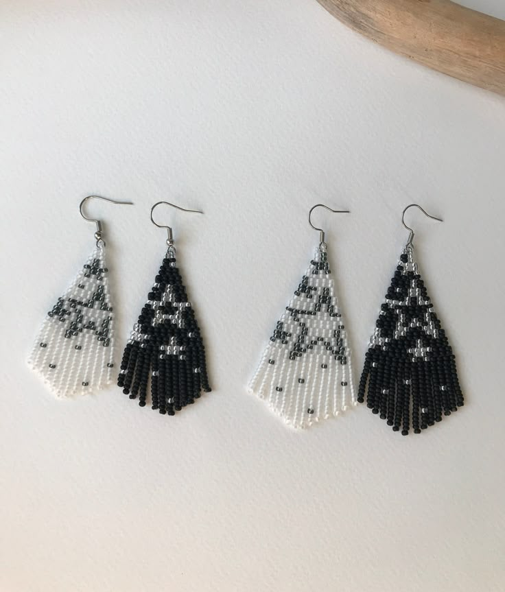 three pairs of beaded earrings hanging on a hook, one with black and white beads