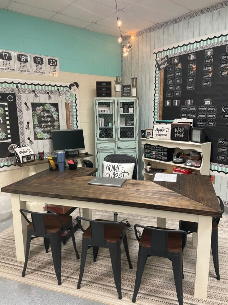 a table with some chairs around it in front of a chalkboard wall and shelves