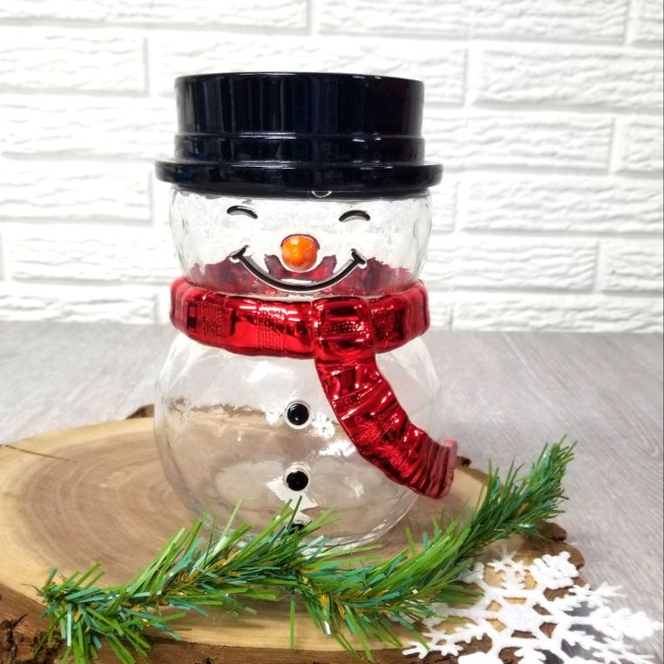 a glass snowman sitting on top of a wooden board