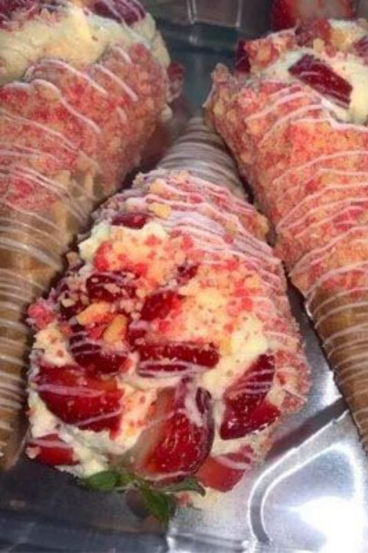 some very tasty looking ice cream cones with strawberries on them in a display case