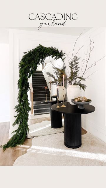 a black table with candles and greenery on it in the middle of a room