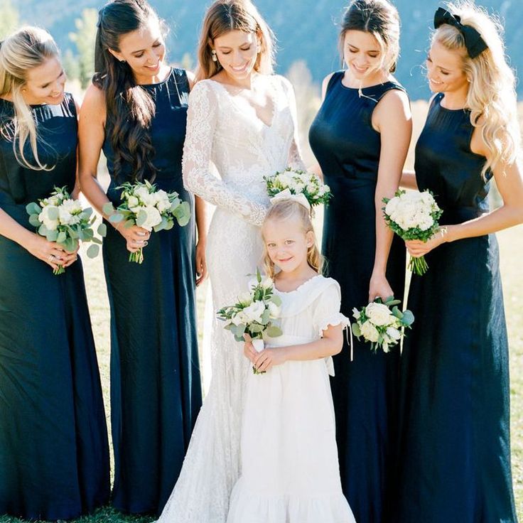 a group of women standing next to each other on top of a grass covered field