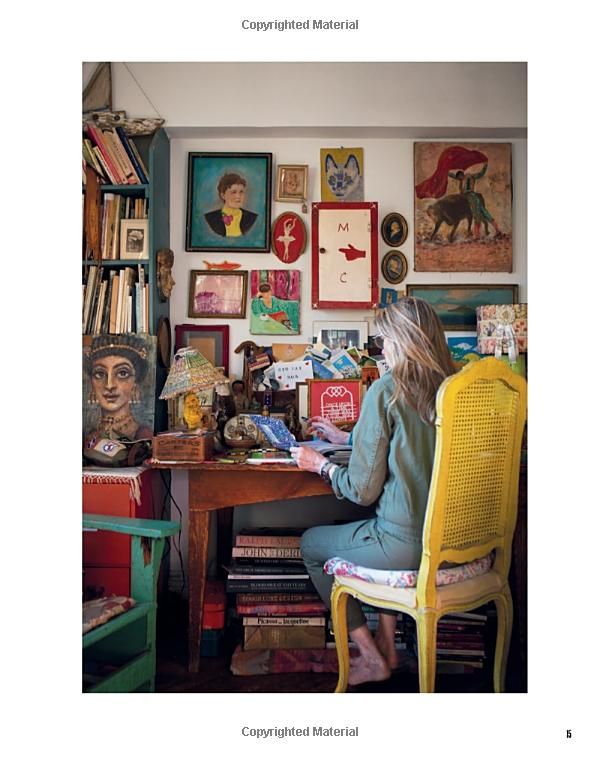 a woman sitting at a desk in front of a wall full of pictures and books