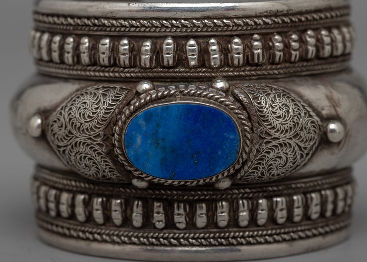 Inlaid Lapis Lazuli Bracelet About The Bracelet: Discover the mesmerizing charm of the carefully made Inlaid Lapis Lazuli Bracelet, which is set on a silver. The rich, deep blue of lapis lazuli is skillfully inlaid into the silver in this gorgeous bracelet, producing an eye-catching, captivating impression. Every section of the bracelet is expertly crafted to accentuate the inherent patterning of the lapis lazuli, guaranteeing that the royal blue tones of the stones contrast magnificently with t Traditional Oval Bracelets As Gift, Traditional Oval Bracelets For Gift, Blue Engraved Jewelry For Ceremonial Occasion, Traditional Oval Bracelet For Gift, Ceremonial Blue Engraved Jewelry, Blue Ceremonial Bracelet Jewelry, Blue Ceremonial Bangle Jewelry, Artisan Engraved Blue Bracelets, Ceremonial Blue Bracelet Jewelry