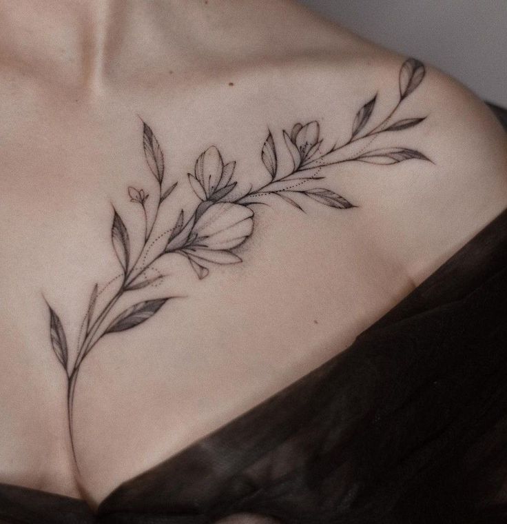 a woman's chest with flowers and leaves tattooed on her left side breast piece