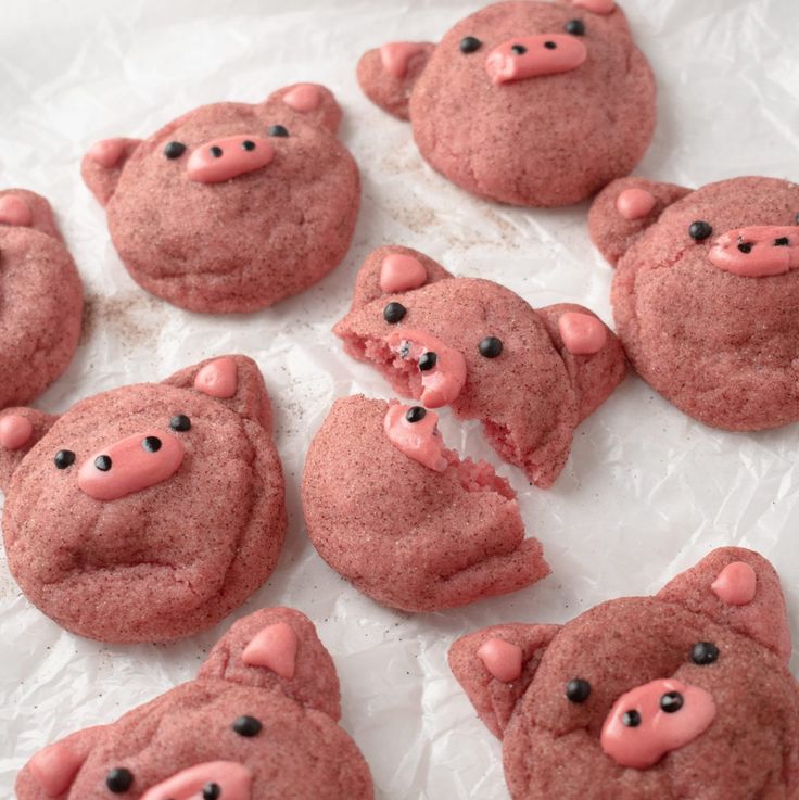 some cookies with pink frosting and black eyes are shaped like pig heads on top of each other