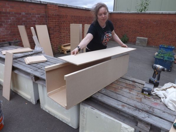 a woman standing next to some cardboard boxes