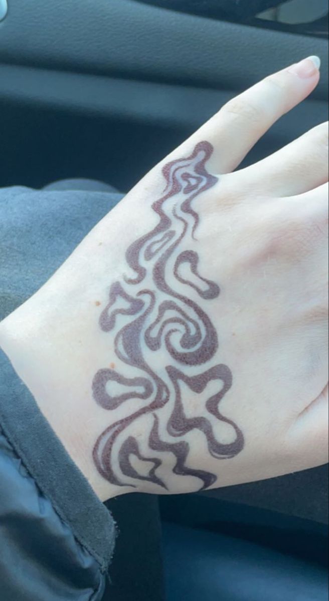 a woman's hand with a tattoo on it sitting in the passenger seat of a car