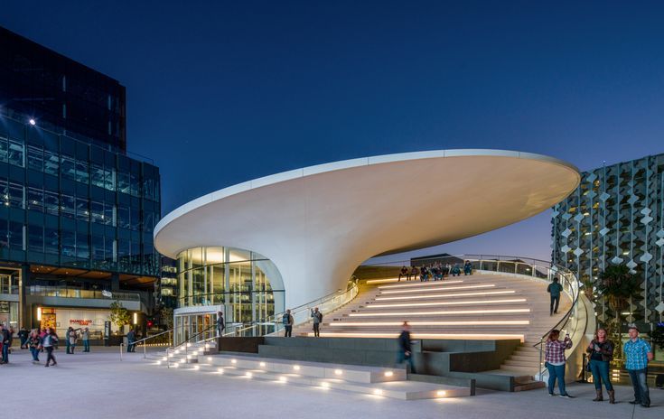 people are walking around in front of a building with stairs and steps leading up to it