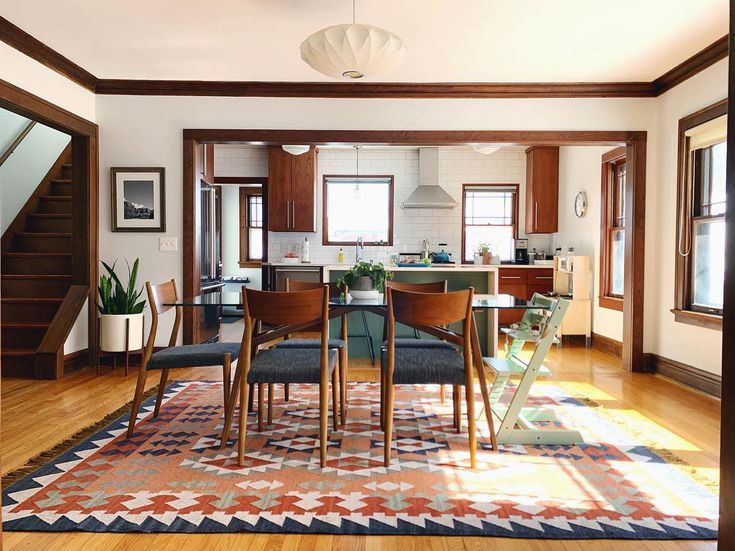 a dining room and kitchen area with hardwood floors, white walls, and wood trimmings