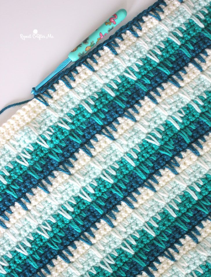 a crocheted blue and white blanket next to a toothbrush