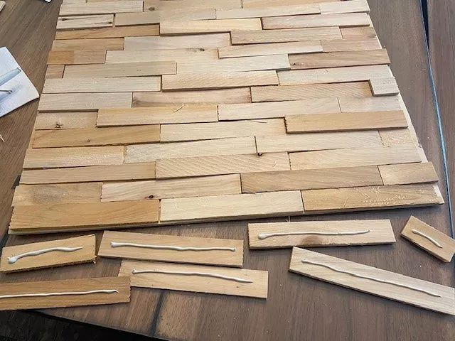 wood planks laid out on a table to make a woven wall hanging or floor mat