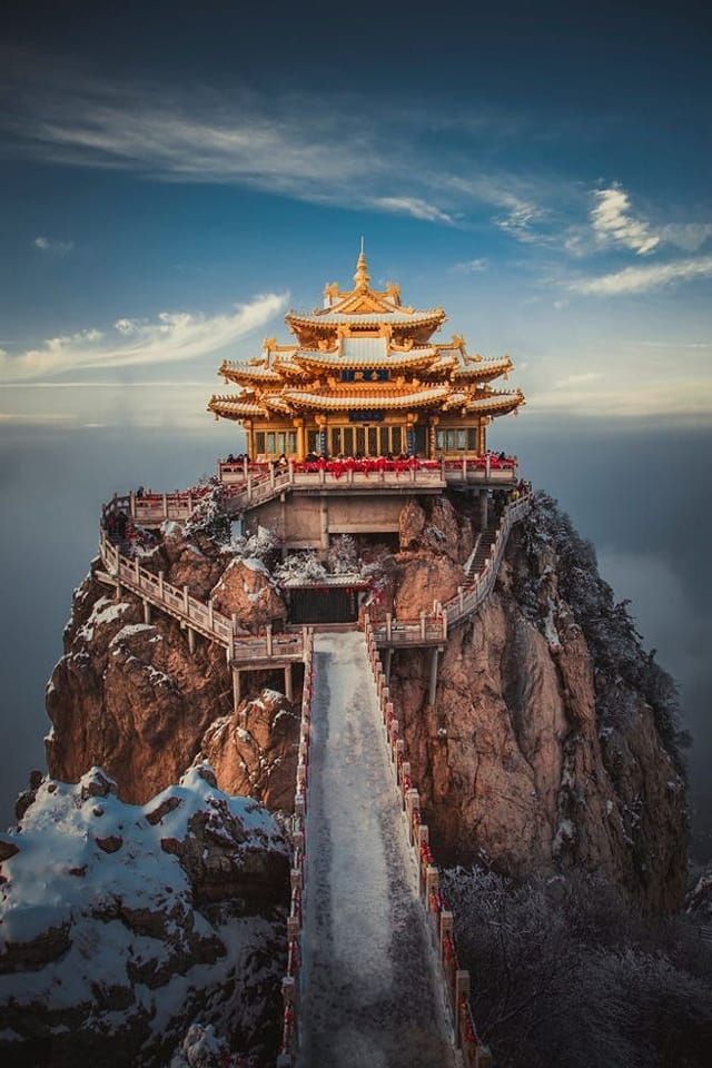 the golden building on top of a mountain with snow covered ground and stairs leading up to it