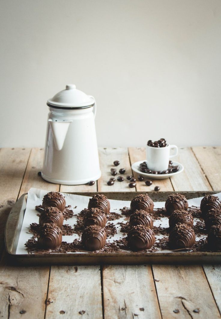 chocolate truffles on a wooden table with a teapot and coffee pot in the background