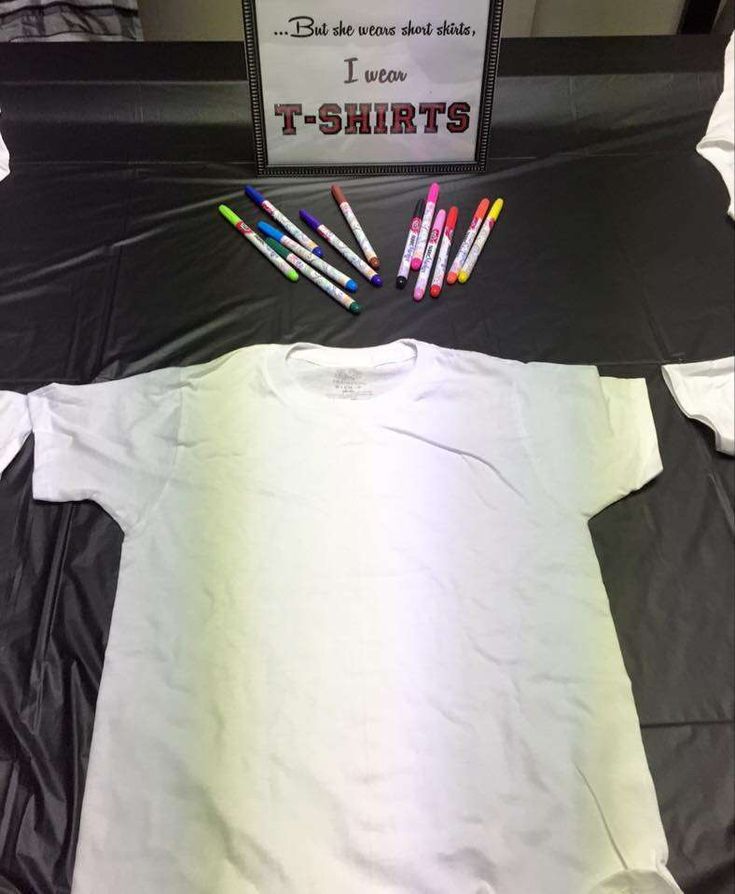 t - shirts are laid out on top of a black and white bed spread with colored crayons