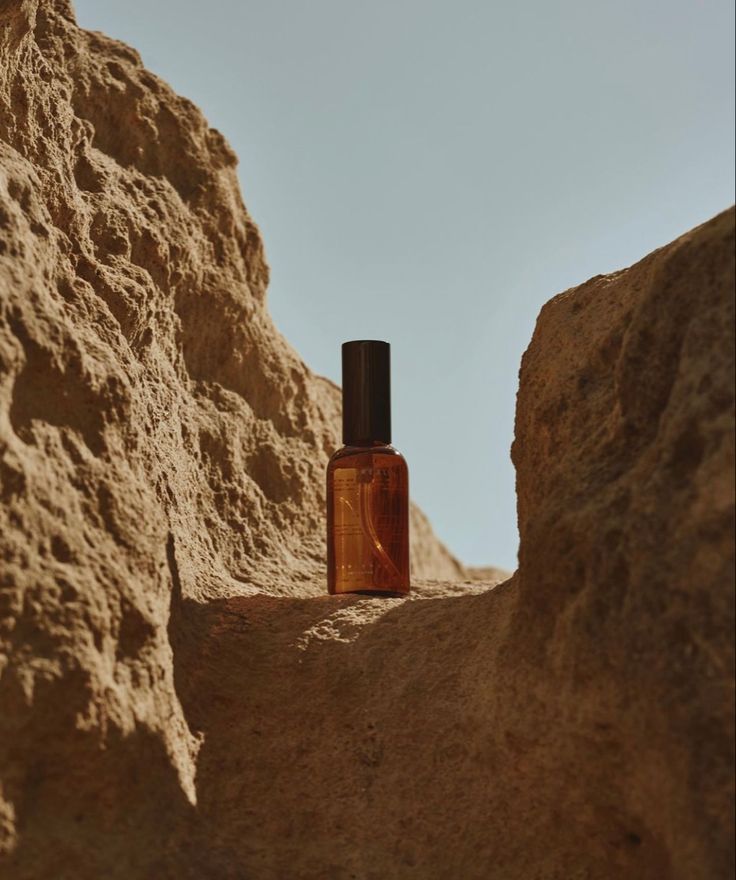 an empty bottle sitting in the middle of some rocks