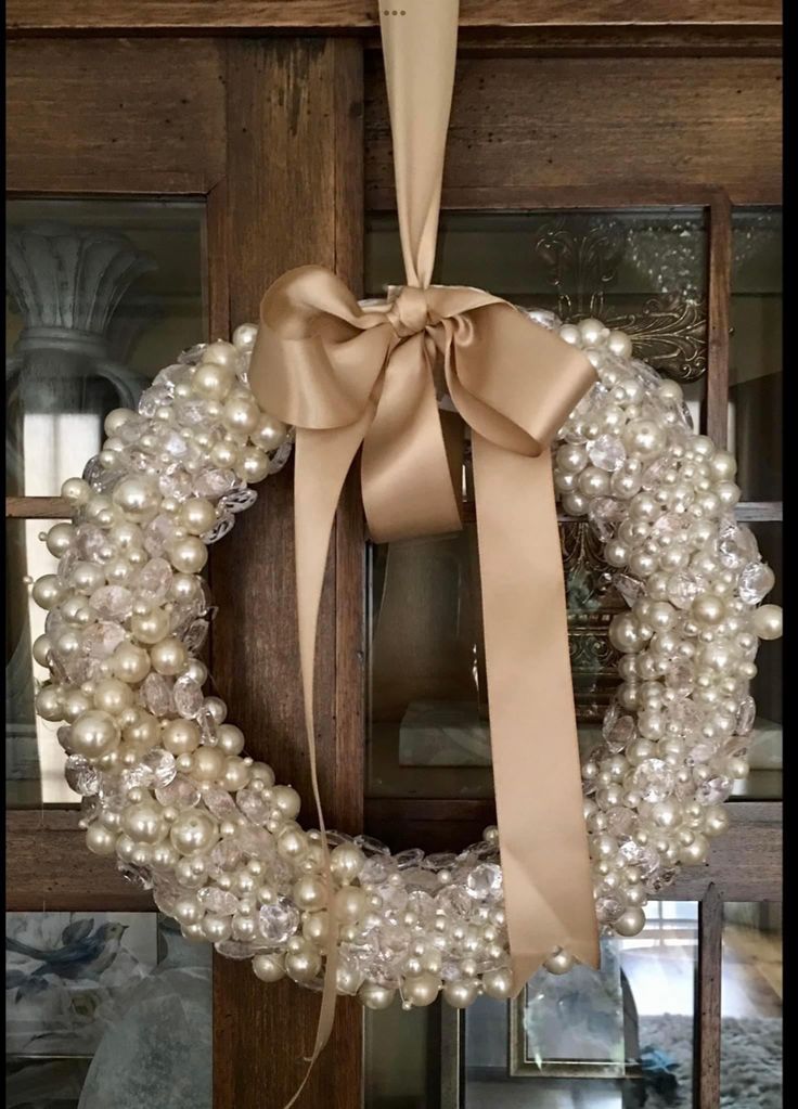 a wreath with pearls and a bow hanging on a door