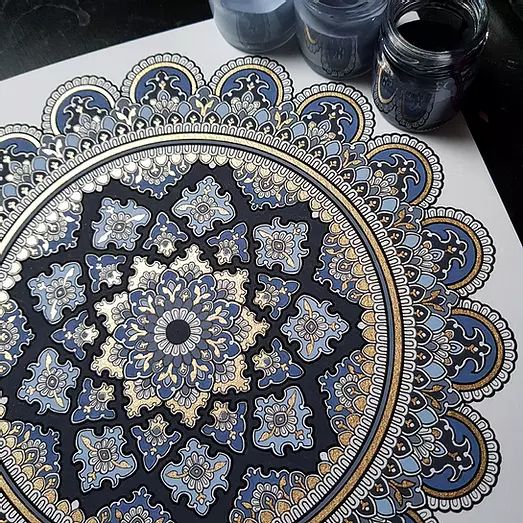 an intricately designed piece of art on a table with some paint and water bottles