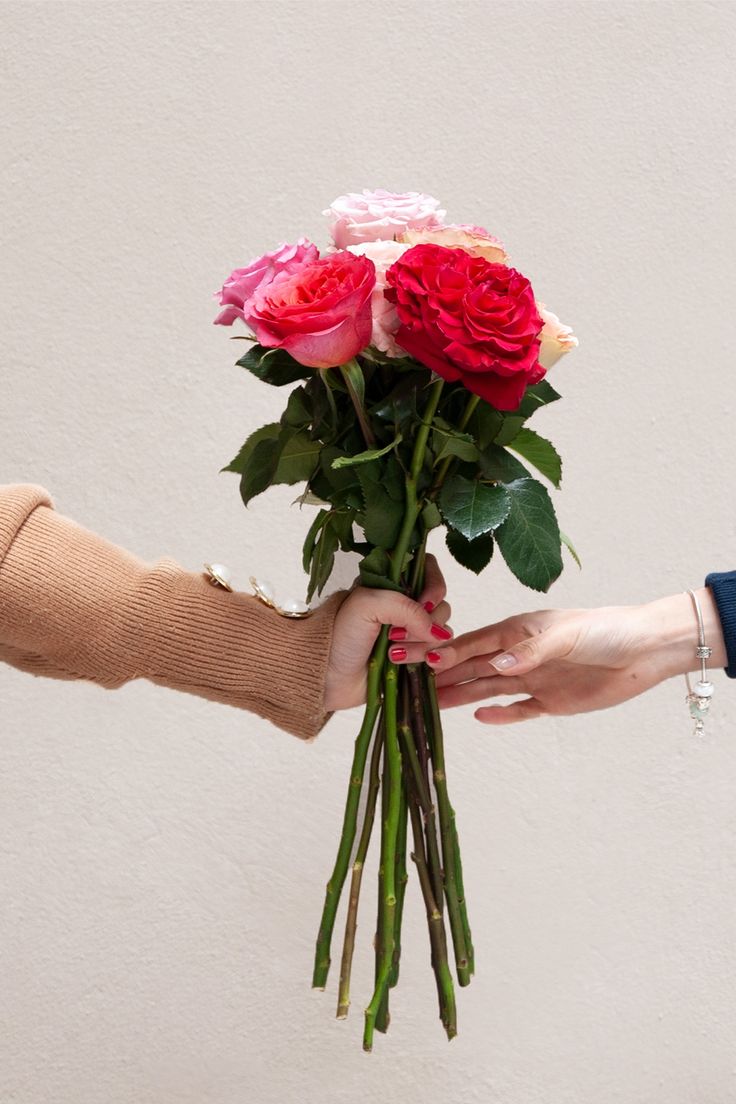 two people holding roses in each other's hands with one hand on the bouquet