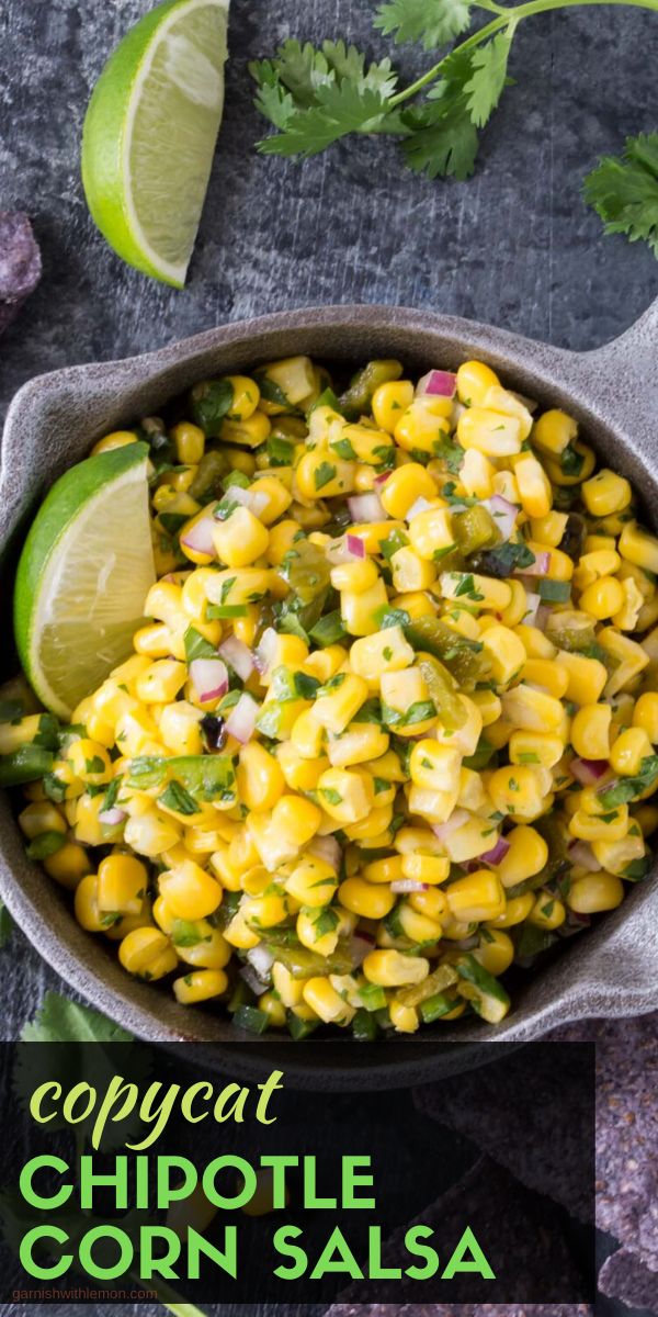 a bowl filled with corn and cilantro on top of a table next to limes