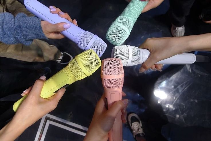 four people holding microphones in their hands with one person pointing at the other hand