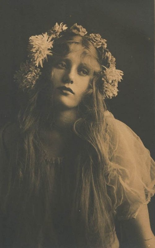 an old photo of a woman with flowers in her hair