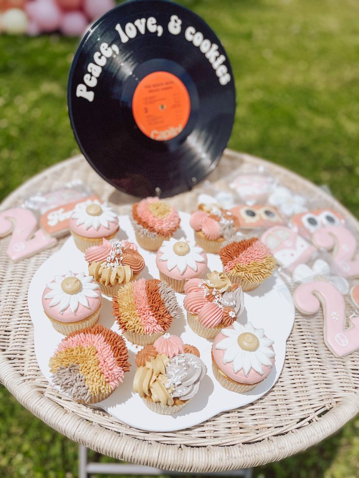 cupcakes and pastries on a wicker table with vinyl record in the background