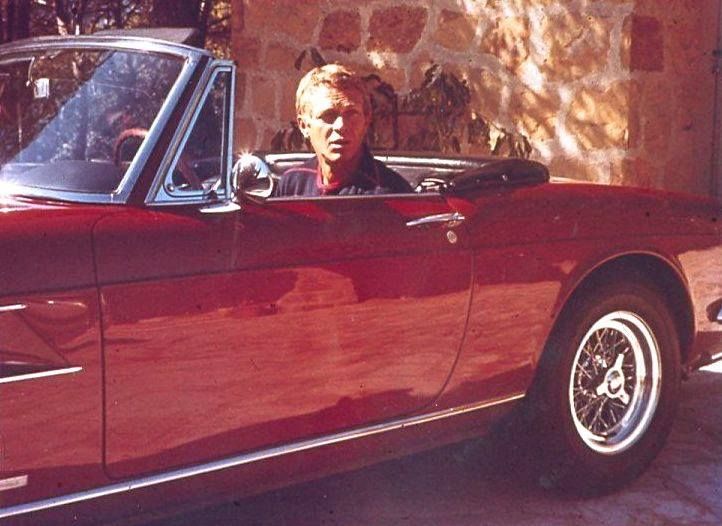 a man sitting in the driver's seat of a red sports car