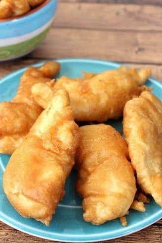 some fried food is on a blue plate and next to two bowls with dipping sauces