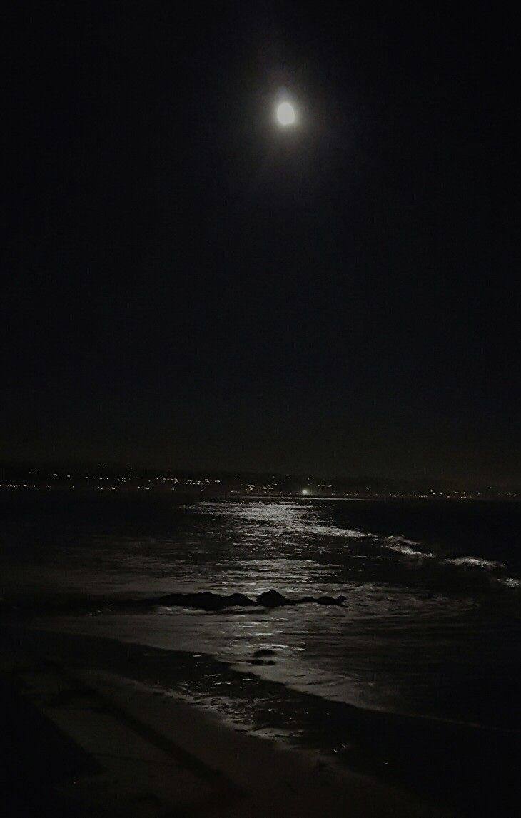 the moon is shining over the ocean at night