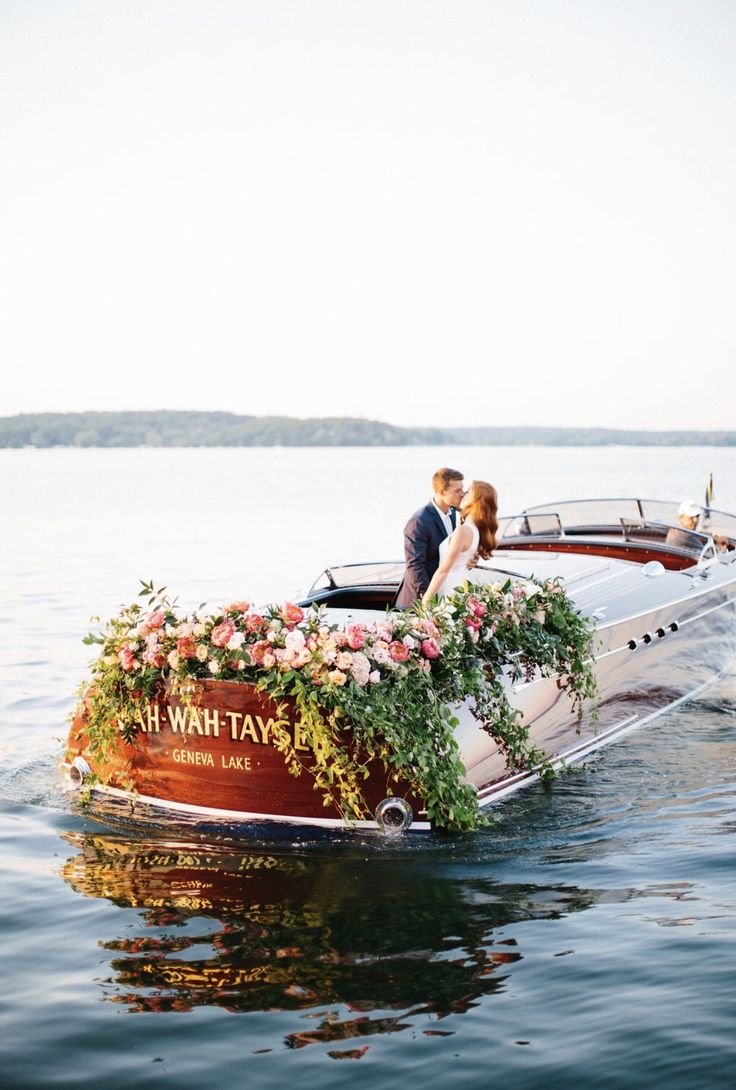 a bride and groom kissing on the back of a boat with flowers growing out of it