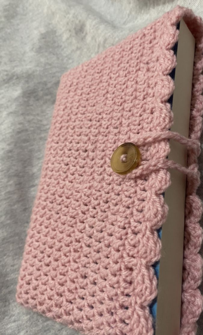 a pink crocheted book with a button on it