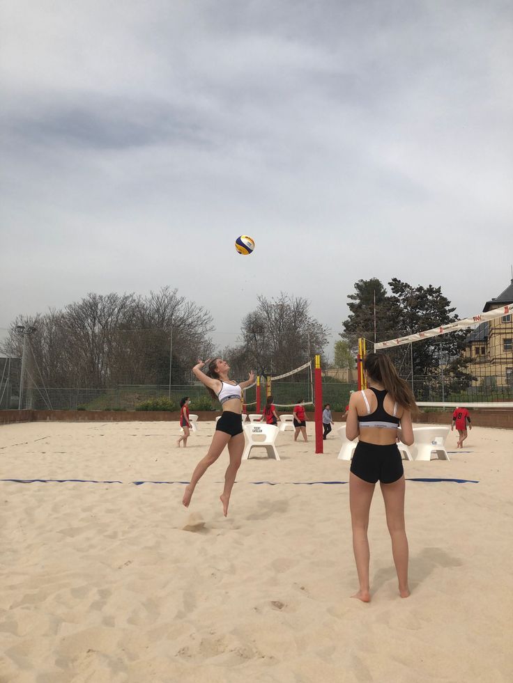 two women playing volleyball in the sand on a beach