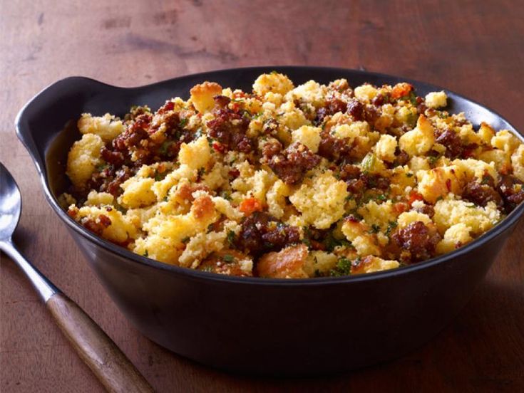 a casserole dish with stuffing in it on a wooden table next to utensils