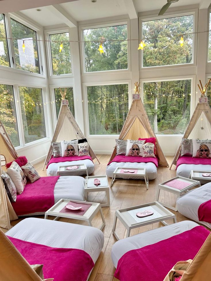 a room filled with lots of pink beds covered in blankets and pillows on top of wooden flooring