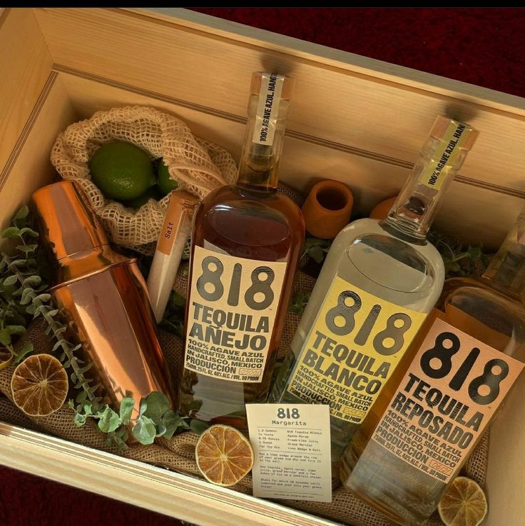 bottles of tequila and oranges in a wooden box with labels on the side,