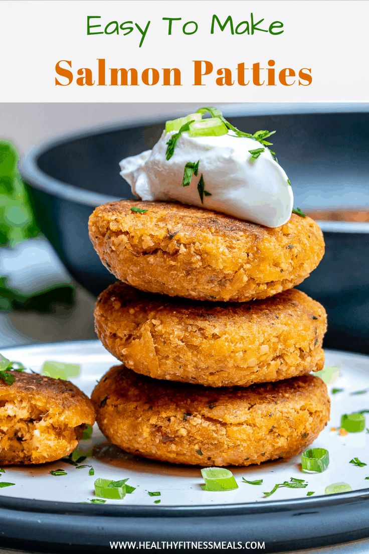 three fried salmon patties stacked on top of each other with sour cream and garnish