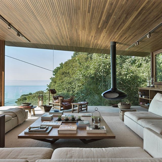 a living room with couches and tables in front of a large window overlooking the ocean