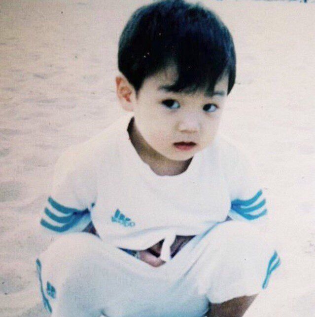 a young boy sitting on top of a sandy beach