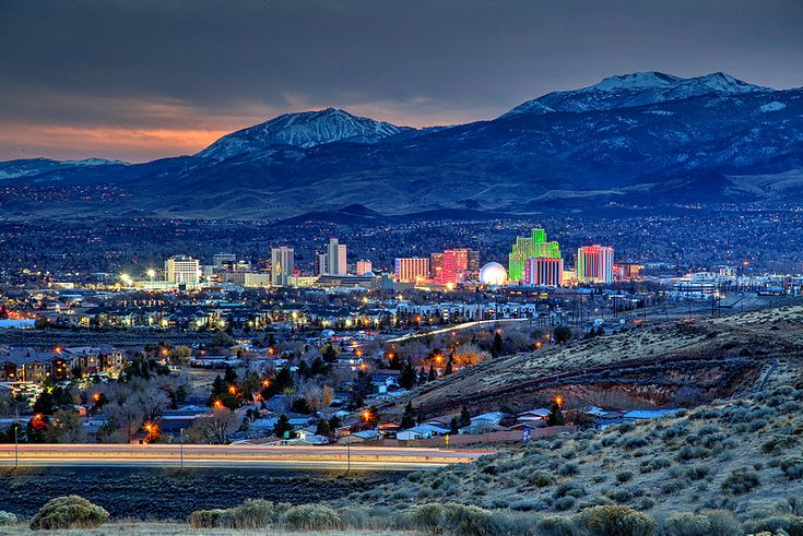 the city is lit up at night in the mountains